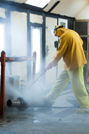 UniTech Services Group employee spraying a part in hazmat gear.