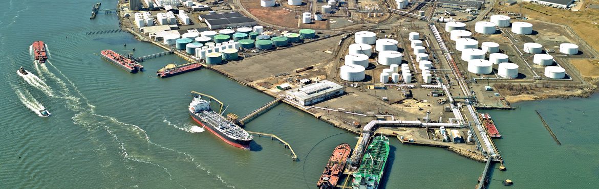 International Liquid Terminal Association aerial view of a liquid terminal showing large round storage tanks on land and boats docked.