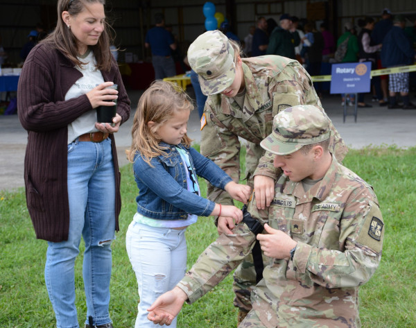 Ithaca Tompkins Regional Airport community day in 2019 showing a young woman helping an army ROTC.