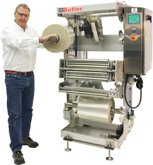 Butler Automatic President Chip Johns holding a roll on a packaging machine.