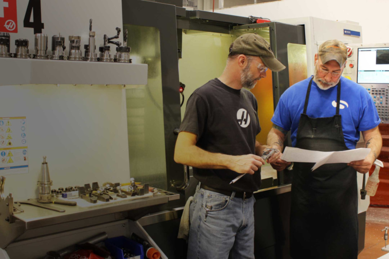 Simplimatic Automation Made In America, two men going over a paper holding a measuring device.