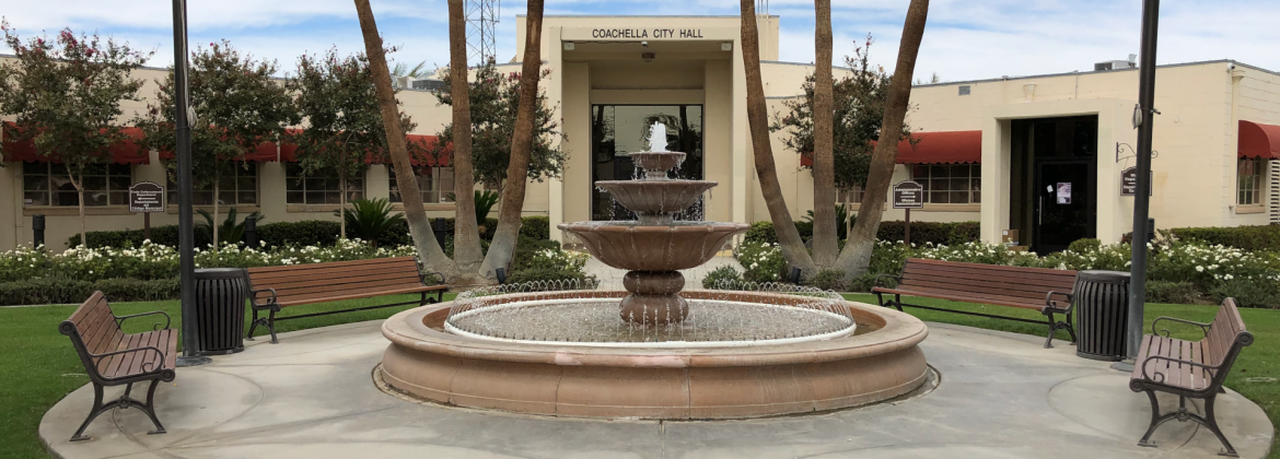 Coachella, California city hall with a fountain and circle area with benches out front.