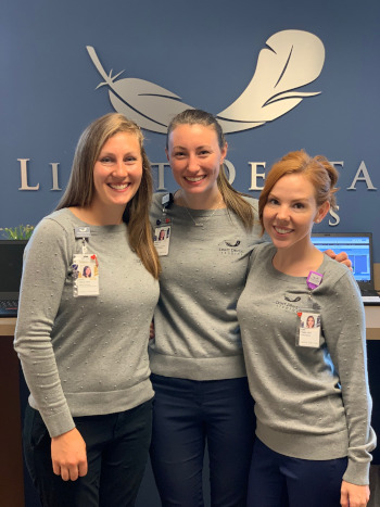 Light Dental Studios employees posing for a photo by front desk.