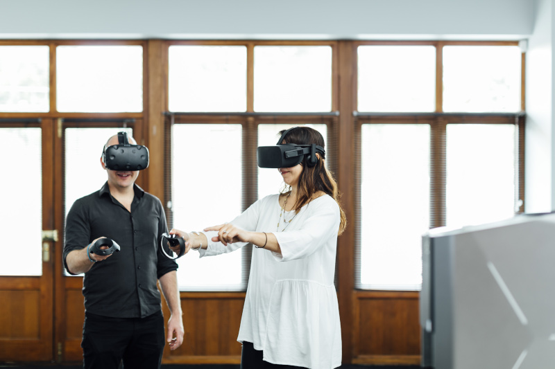 Destination Living, two people trying out augmented reality or virtual reality with headsets and hand controls.