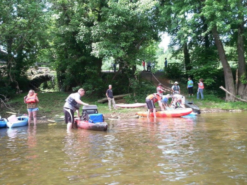 Adair County, Kentucky trail town with people on the shore and kayaks in the water.