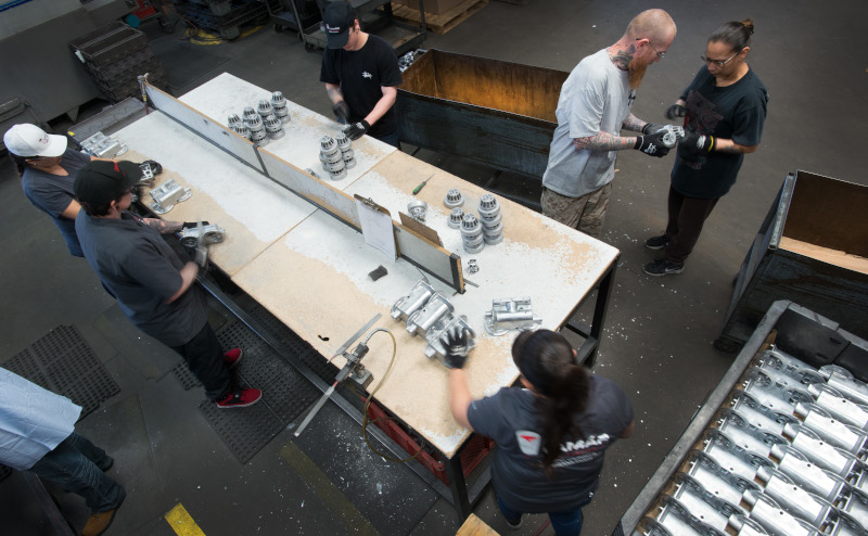 Lamar Tool & Die Casting Inc. employees working around a table on parts.