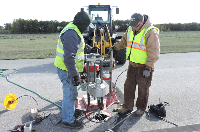 Oscoda-Wurtsmith Airport OWA men working with a machine on the runway.