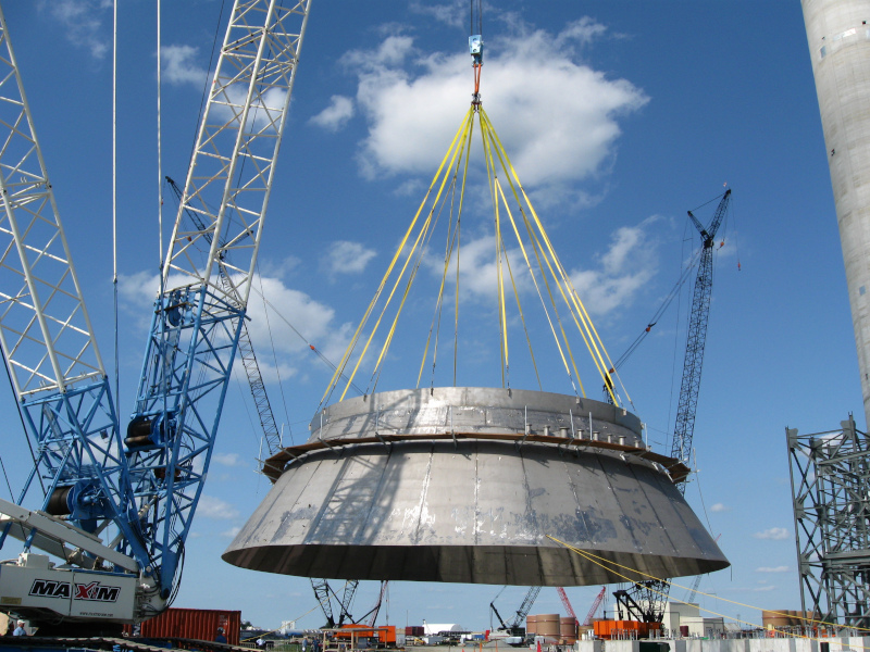 Fisher Tank Company installing a tank with a metal part being lowered on a crane.