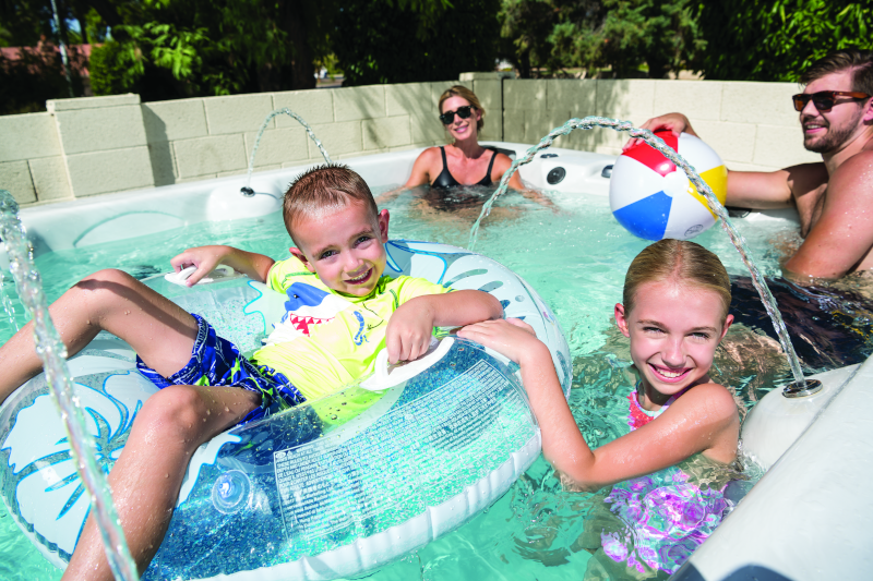 MAAX Spas swim spa boy in tube with family.