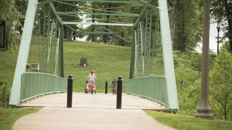 Trussville, Alabama truss bridge with a woman and child riding on bikes across.