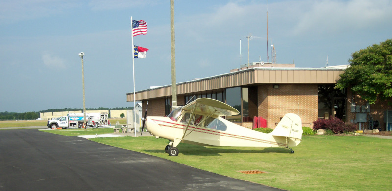 Lumberton Municipal Airport building with a plane out front.