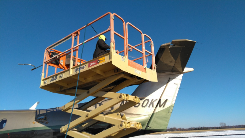 Allen County Airport worker de-icing a plane on a lift