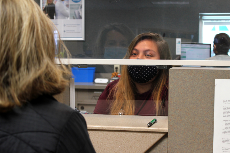 A Triangle Credit Union teller assist a member through plexiglass in Nashua, NH.